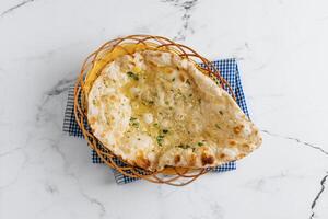 crocantes alho naan dentro uma cesta isolado em guardanapo lado Visão em cinzento fundo famoso indiano e paquistanês Comida foto