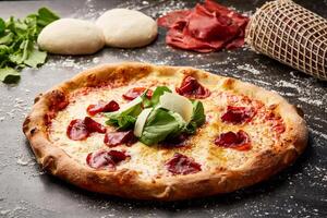 Bresaola e foguete pizza isolado em Sombrio fundo com cru Comida topo Visão do italiano comida rápida Aperitivo foto