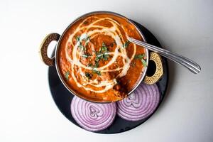 manteiga frango karahi ou frango makhni com cebola e Pimenta servido dentro uma prato isolado em cinzento fundo topo Visão do Bangladesh Comida foto