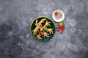 cozido no vapor frango pés com Primavera cebola, alho e peixe molho servido dentro tigela isolado em Sombrio cinzento fundo topo Visão do japonês Comida foto