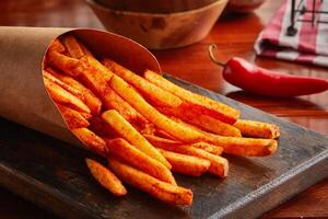 picante francês fritas servido dentro uma de madeira borda isolado em de madeira fundo lado Visão foto