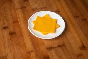 quadrado queijo fatia amarelo servido dentro prato isolado em de madeira mesa topo Visão do indiano Comida foto