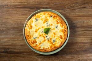 quattro Formaggi pizza servido dentro uma prato topo Visão em Sombrio de madeira fundo foto