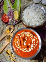 frango Makhani ou manteiga frango com arroz, salada e de madeira colher servido dentro uma prato isolado em mesa lado Visão foto