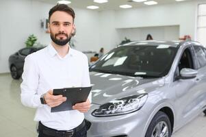 fechar-se tiro do bem sucedido confiante sorridente caucasiano masculino fazer compras assistente segurando prancheta dentro formal roupas às automóvel carro revendedor fazer compras foto