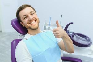 jovem homem às a dentista. dental Cuidado, levando Cuidado do dentes. cenário com cópia de espaço para fundo. foto