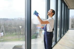 jovem homem lavando janela dentro escritório foto