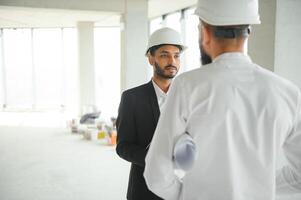 construção conceito do multirracial engenheiro e arquiteto trabalhando às construção local com azul impressão foto