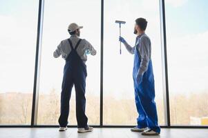 costas Visão do multicultural profissional trabalhadores lavando ampla panorâmico janelas dentro escritório foto