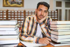 masculino indiano aluna às a biblioteca com livro foto