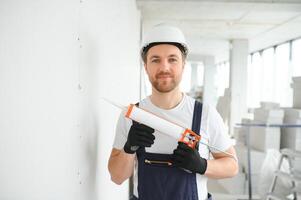 profissional trabalhador aplicando silicone selante com calafetagem arma de fogo em a parede foto