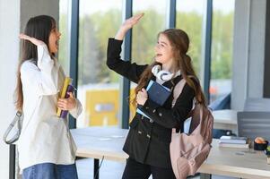 sorridente meninas dentro Alto escola corredor. dois fêmea Faculdade alunos falando depois de palestra. foto