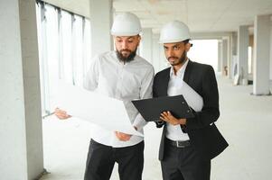 multirracial masculino colegas de trabalho dentro capacetes discutindo projeto em construção local foto