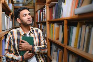 feliz inteligente indiano ou árabe cara, misturado raça macho, universidade estudante, dentro a biblioteca foto