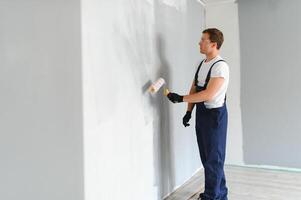 jovem trabalhador pintando parede no quarto foto