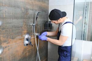 encanador instalando água torneiras chuveiro parar, trabalhos dentro banheiro. foto