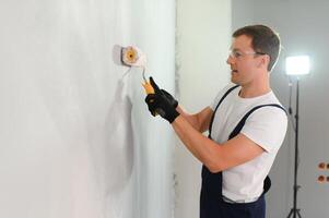 jovem trabalhador pintando parede no quarto foto