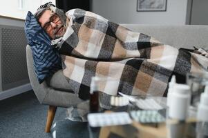 homem embrulhado dentro xadrez em a sofá sentindo-me doente doença às casa foto