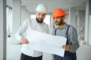 multirracial masculino colegas de trabalho dentro capacetes discutindo projeto em construção local foto