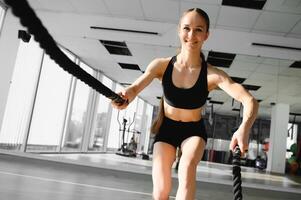 uma menina é fazendo exercícios usando Esportes equipamento - uma corda, jogando Esportes dentro a academia. foto