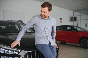 final decisão. tiro do uma bonito jovem homem em pé dentro frente do uma Novo carro às a concessionária pensando fricção dele queixo foto