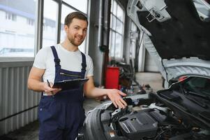 carro serviço, reparar, manutenção e pessoas conceito - feliz sorridente auto mecânico homem ou ferreiro com prancheta às oficina foto