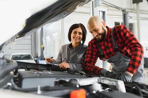 masculino e fêmea mecânica trabalhando em carro foto