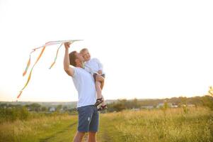 feliz do pai dia. criança menina e Papai com uma pipa em natureza dentro verão foto