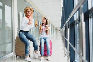 mãe com dela filha às aeroporto terminal com malas comendo velozes Comida foto