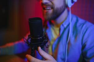 masculino rádio hospedeiro com fones de ouvido em cabeça e microfone dentro estúdio lendo notícia ou transmissão mostrar, tonificado foto