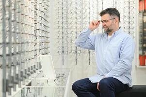 masculino cliente escolhendo óculos dentro óptica loja foto