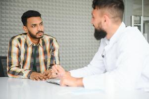 medicamento, cuidados de saúde e pessoas conceito - feliz médico com prancheta e jovem masculino paciente encontro às hospital foto