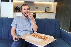 homem comendo pizza tendo uma Leve embora às casa relaxante em repouso foto