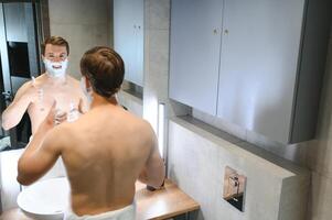 confiante cara usando barbeador dentro banheiro foto