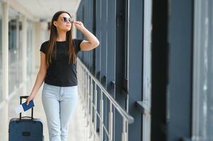 jovem mulher puxar mala de viagem dentro aeroporto terminal. cópia de espaço foto