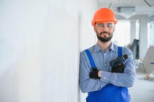 retrato do positivo, bonito jovem masculino construtor dentro Difícil chapéu enquanto trabalhando às construção local foto