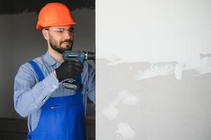 homem drywall trabalhador instalando placa de gesso Folha para parede foto