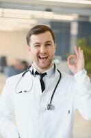 retrato do sorridente médico dentro uniforme em pé dentro remédio clínica corredor foto