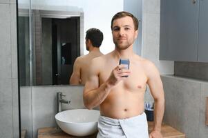 reflexão do jovem homem dentro espelho barbear com elétrico barbeador foto