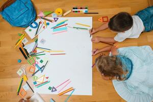 crianças desenhando em chão em papel. pré escola Garoto e menina jogar em chão com educacional brinquedos - blocos, trem, Ferrovia, avião. brinquedos para pré escola e Jardim da infância. crianças às casa ou creche. topo visualizar. foto