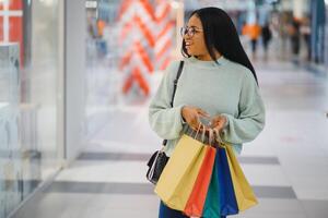 lindo Preto mulher sorridente e segurando compras bolsas. foto