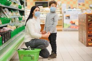 mãe e criança dentro supermercado junto, elas ir compras livremente sem uma mascarar depois de quarentena, escolher Comida junto. foto