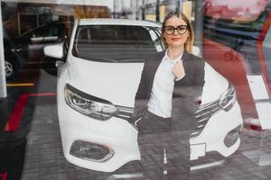 o negócio mulher compra uma carro às uma carro concessionária. conceito do feliz o negócio pessoas foto