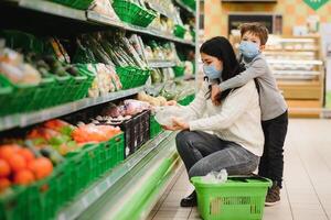 mãe e criança dentro supermercado junto, elas ir compras livremente sem uma mascarar depois de quarentena, escolher Comida junto. foto