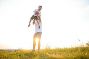 feliz pai jogando com filho em pôr do sol fundo .o conceito do do pai dia foto
