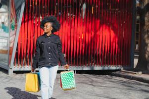 atraente jovem afro-americano mulher compras - compras bolsas, ao ar livre, rua visualizar, adequado para feriado compras temas, entre outras foto