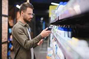 sorridente homem escolhe xampu dentro supermercado foto