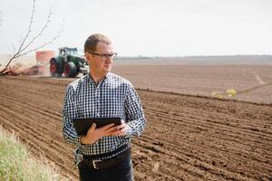 agricultor dentro campo examinando semeadura e segurando tábua dentro dele mãos. foto