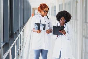 bem sucedido africano americano médico trabalhadores estudando pacientes raio X foto