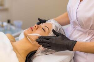 uma menina às uma cosmetologista faz Cosmético procedimentos. pele limpeza foto